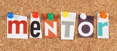 The word Mentor in cut out magazine letters pinned to a cork notice board. Mentors are seen as an investment in people via inspiration,motivation and the sharing of ideas and experiences.